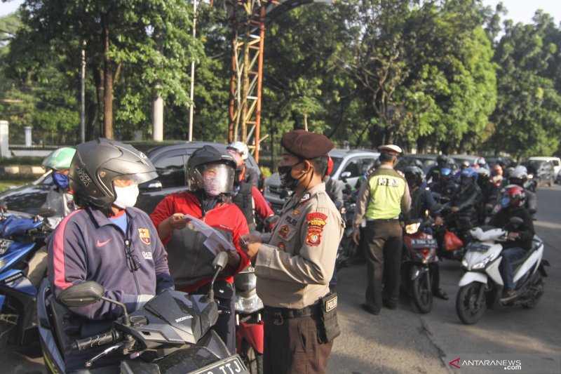 Petugas kepolisian memeriksa identitas pengendara motor yang berpenumpang saat penerapan Pembatasan Sosial Berskala Besar (PSBB), di Perbatasan Jakarta - Depok, Depok, Jawa Barat, Rabu (15/4/2020). Pemeriksaan tersebut untuk memastikan setiap pengendara mematuhi aturan PSBB yang diterapkan di Kota Depok. ANTARA FOTO/Asprilla Dwi Adha/hp.
