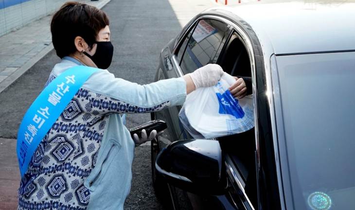 Seorang penjaga toko memberikan makanan di pojok drive through sashimi, di Seoul, Korea Selatan, Minggu (5/4/2020). (REUTERS/KIM HONG-JI)