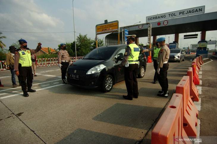 Personel kepolisian mengarahkan kendaraan untuk memutar balik di gerbang tol Pejagan, Brebes, Jawa Tengah, Rabu (29/4/2020). Polres Brebes dan pihak Pejagan Pemalang Tol Road (PPTR) melakukan penutupan di jalan tol Pejagan-Pemalang, seluruh kendaraan dari arah Jakarta dikeluarkan melalui gerbang tol Brebes Timur dan Pejagan untuk dilakukan penyekatan dan memutar arah kembali ke Jakarta. ANTARA FOTO/Oky Lukmansyah/foc.