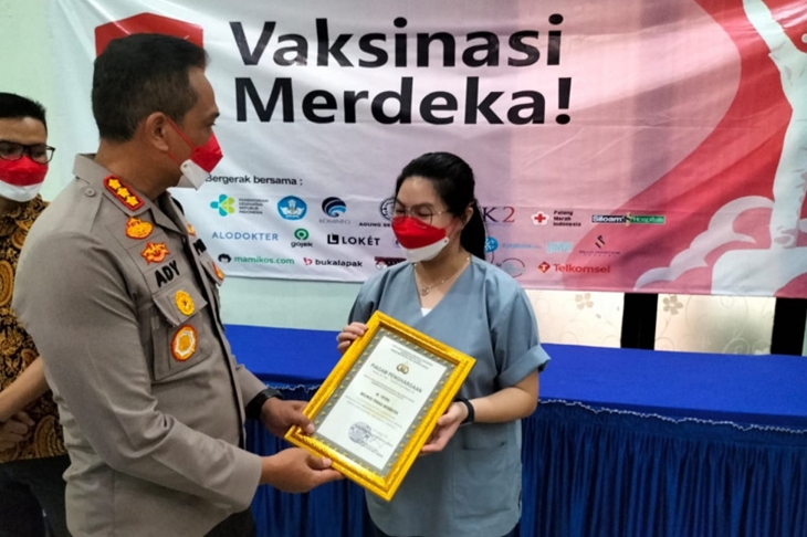 Kapolres Metro Jakarta Barat Kombes Pol Ady Wibowo (kiri) memberikan penghargaan kepada salah satu dokter dan relawan tenaga kesehatan Yuvina yang terlibat dalam kegiatan "Vaksinasi Merdeka" di Jakarta Barat, Selasa (17/8/2021). ANTARA/Walda Marison