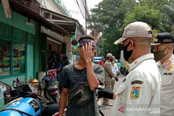 Pelanggar PSBB menutup mukanya akibat malu saat diminta menyanyikan lagu nasional sebagai hukuman dari petugas Satpol PP Cempaka Putih karena tidak pakai masker di tengah PSBB, Rabu (13/5/2020). (ANTARA/HO/Dokumentasi Satpol PP Cempaka Putih)