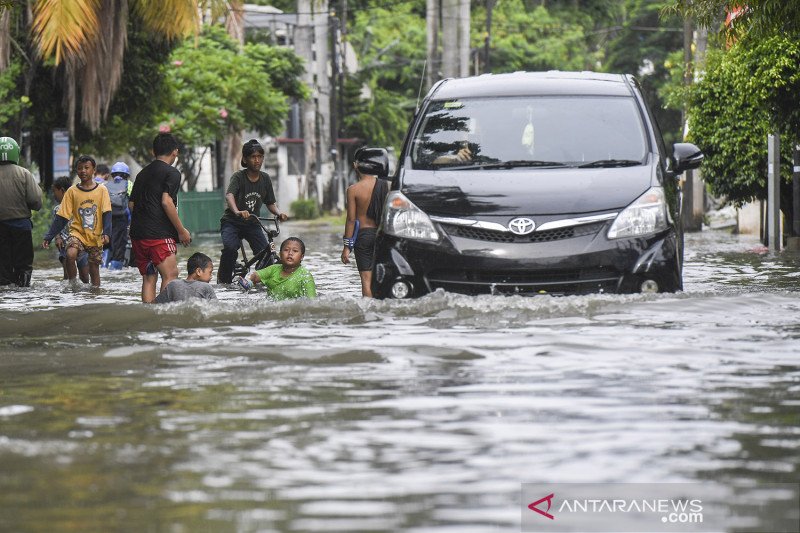 Sejumlah anak bermain di genangan air di kawasan perumahan Green Garden, Jakarta, Minggu (7/2/2021). Hujan deras yang mengguyur Jakarta pada Minggu (7/2) dini hari menyebabkan kawasan tersebut tergenang air dengan ketinggian 30-50 cm sehingga mengganggu aktivitas warga. ANTARA FOTO/Hafidz Mubarak A/aww.