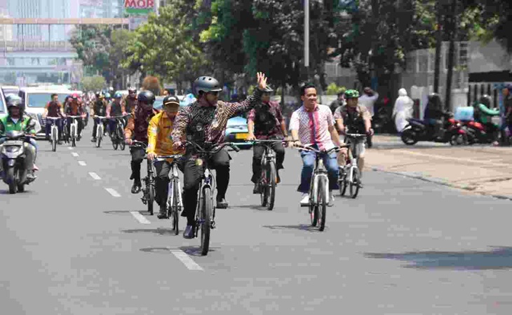 Bersepeda sambil mengenakan baju Batik Anies melambaikan tangan kepada masyarakat