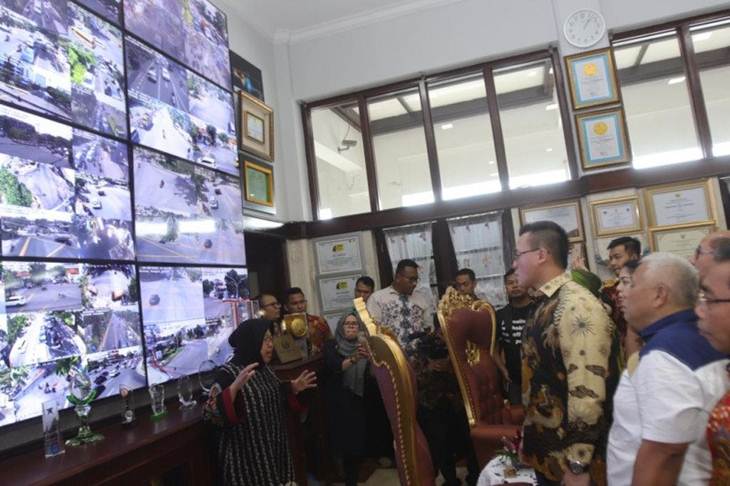 Wali Kota Surabaya Tri Rismaharini menunjukkan layar monitir raksasa yang memantau kondisi Kota Surabaya dihadapan puluhan anggota DPRD DKI Jakarta saat melakukan kunjungan kerja di ruang kerjanya, Jumat (20/12/2019). (HO)
