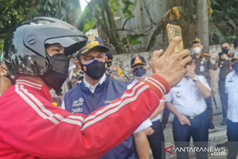 Gubernur DKI Jakarta Anies Baswedan (kanan) swafoto bersama pengendara di pos penyekatan PPKM Darurat kawasan Daan Mogot, Jakarta Barat, Rabu (7/7/2021). ANTARA/HO-Humas Polres Metro Jakarta Barat