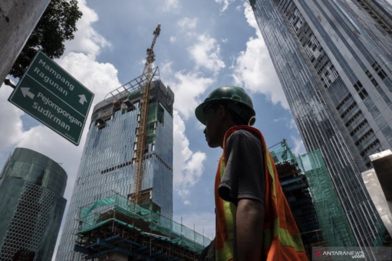 Pekerja melintas dengan latar belakang pembangunan gedung bertingkat di kawasan Kuningan, Jakarta, Jumat (3/4/2020). ANTARA FOTO/Dhemas Reviyanto/pras.
