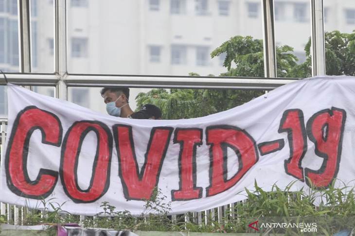 Warga berjalan dengan latar depan spanduk bertuliskan COVID-19 di Jalan Margonda, Depok, Jawa Barat, Kamis (12/3/2020) yang mengajak warga agar tidak panik tapi tetap waspada terhadap penyebaranCOVID-19. ANTARA/Asprilla Dwi Adha/aww.