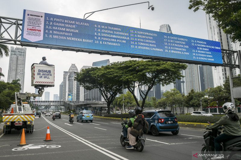 Petugas Dinas Perhubungan DKI Jakarta mengecek papan informasi mengenai kebijakan sistem pembatasan kendaraan bermotor berdasarkan nomor plat nomor ganjil-genap di kawasan Jalan Sudirman, Jakarta, Senin (24/8/2020). ANTARA FOTO/Galih Pradipta