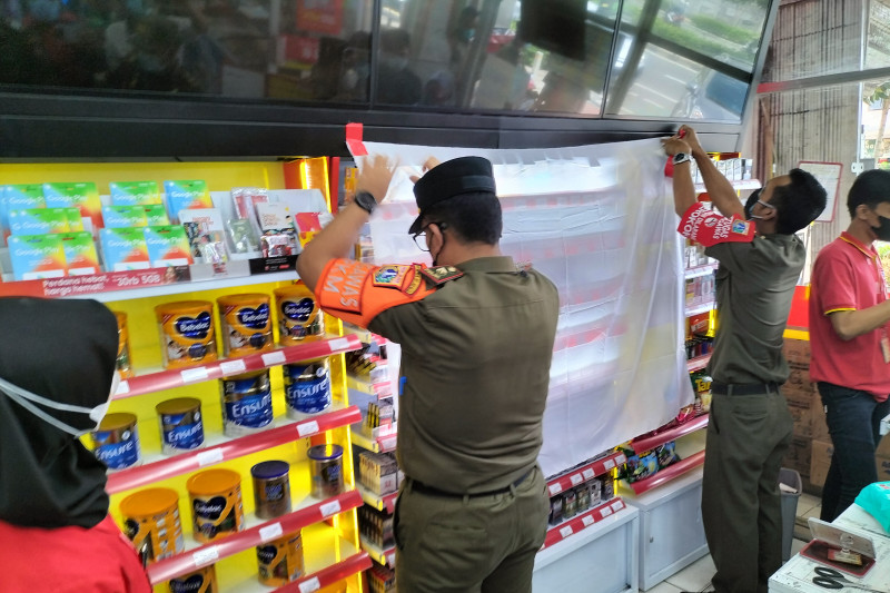 Satpol PP Jakarta Barat saat menutup pajangan produk rokok di salah satu toko swalayan kecil di Jakarta Barat, Senin (12/9). ANTARA/Waldac