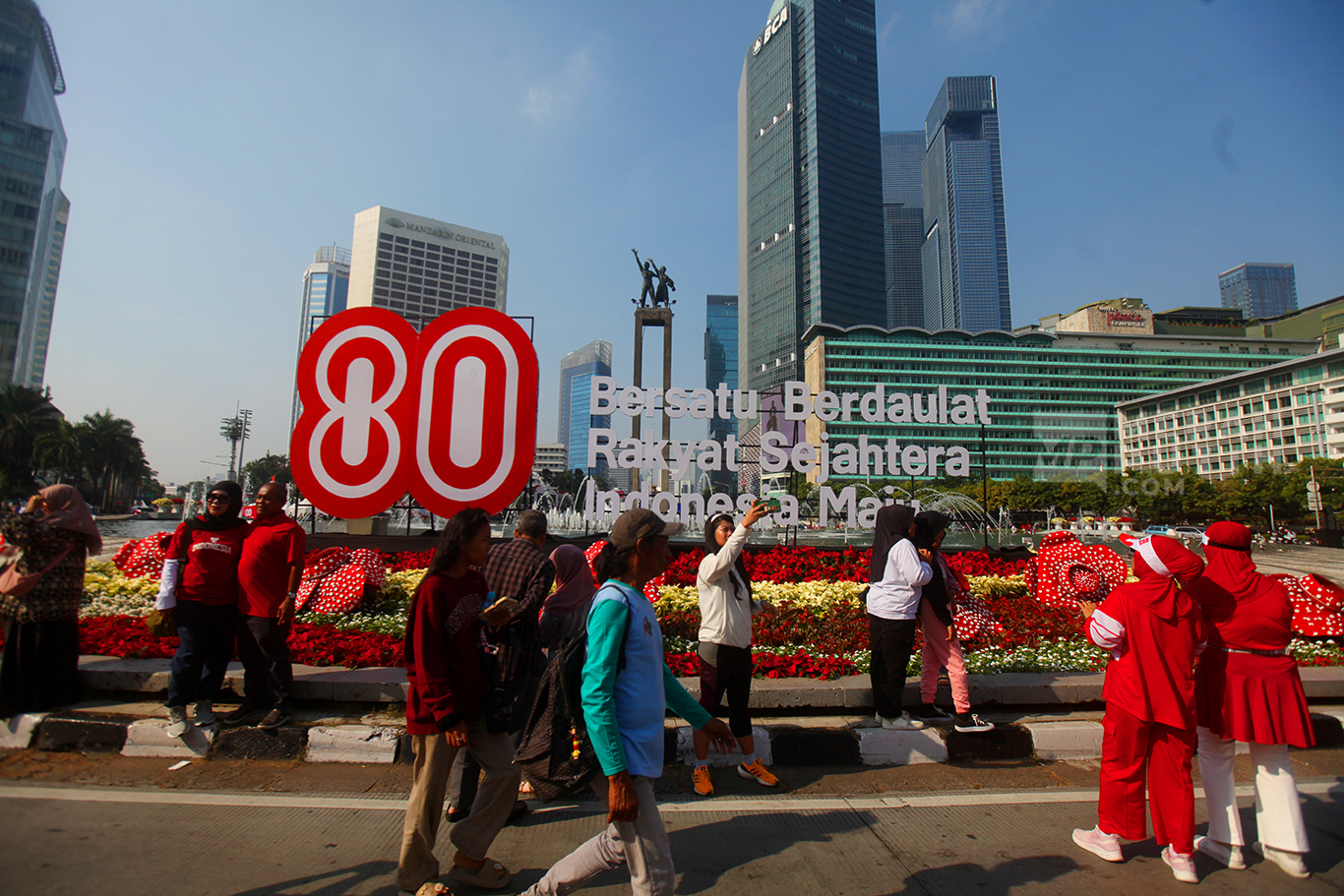 Sejumlah warga berfoto dengan latar Logo resmi HUT ke-80 RI di Bundaran HI, Jakarta, Minggu (17/8/2025).