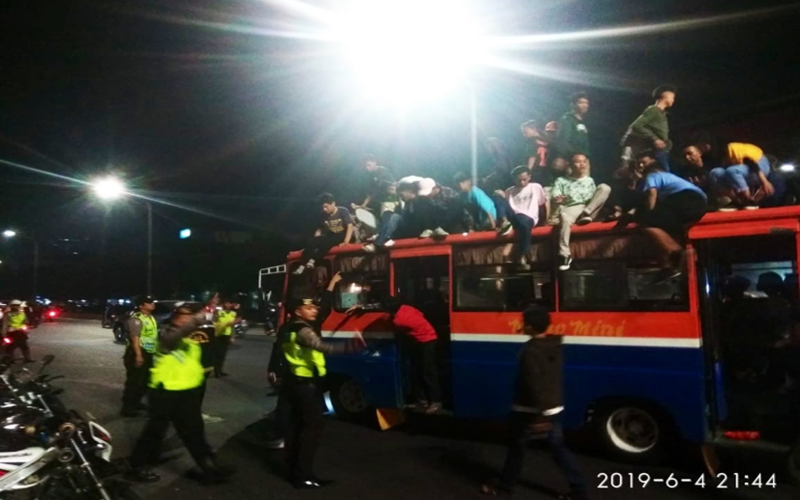 Petugas kepolisian mengamankan warga yang pawai takbiran dengan menaiki atap angkot di Jakarta
