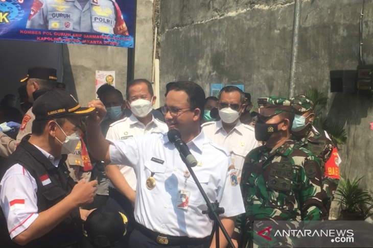 Gubernur DKI Jakarta Anies Baswedan memakaikan topi dinas yang ia kenakan kepada Ketua RW 05 Kelurahan Sunter Agung Nurus Shobah usai meninjau pelaksanaan pendataan dan pemeriksaan antigen kepada warga RW 05 yang mengikuti arus balik pada Rabu (19/5/2021). (ANTARA/Abdu Faisal)