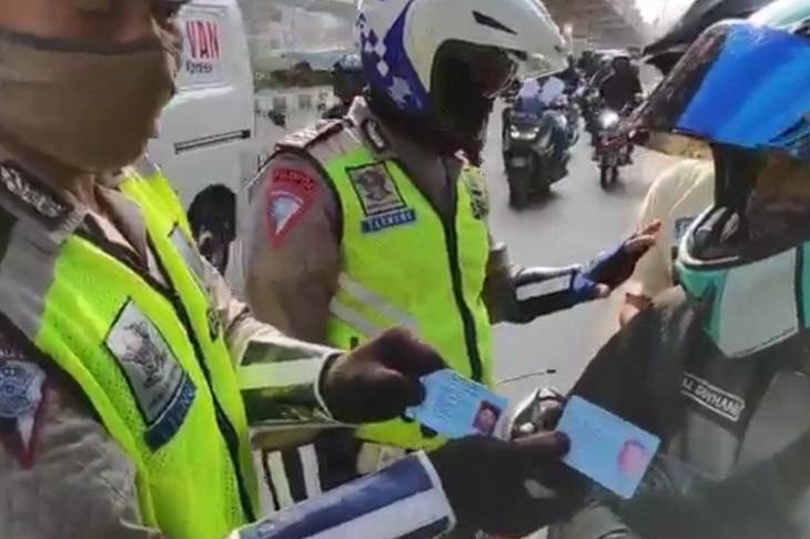 Petugas Pos Cek Poin Kalimalang, Jakarta Timur, mengecek alamat pengendara motor pada alamat KTP dalam rangka penegakan aturan Pembatasan Sosial Berskala Besar (PSBB), Senin (20/4/2020). (ANTARA/HO-Polrestro Jaktim)