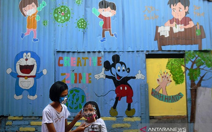 Anak-anak masker pelindung wajah saat bermain di depan mural bertema COVID-19 di Jakarta, Senin (27/7/2020). ANTARA FOTO/Akbar Nugroho Gumay/pras/aa.