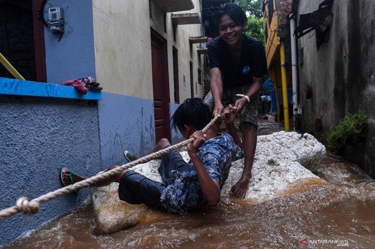 Warga berpegangan pada tali saat banjir melanda Cipinang Melayu, Jakarta Timur, Jumat (19/2/2021). ANTARA FOTO/Sigid Kurniawan/foc.