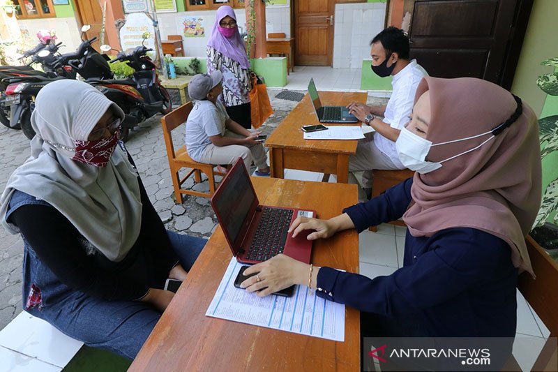 Dua orang guru membantu wali murid mengisi data saat Penerimaan Peserta Didik Baru (PPDB) daring jalur zonasi tingkat SMP di SD Negeri Pesantren 2, Kota Kediri, Jawa Timur, Kamis (25/6/2020). Sejumlah SD di daerah itu membuka layanan bantuan pendaftaran PPDB daring ke jenjang SMP kepada alumninya agar tidak terjadi kesalahan dalam mendaftar karena kekurangtahuan wali murid. ANTARA FOTO/Prasetia Fauzani/nz