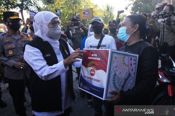 Gubernur Jatim Khofifah Indar Parawansa (tengah) didampingi Kapolda Jatim Irjen Pol Nico Afinta (kiri) di sela membagian paket bantuan kepada warga terdampak PPKM darurat di kawasan Bulak Banteng di Surabaya, Minggu (18/7/2021) sore. (ANTARA/Didik Suhartono)