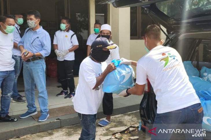 Petugas menyerahkan bantuan bahan pokok kepada salah seorang warga terdampak secara ekonomi akibat wabah virus corona (COVID-19) di Pospol Waduk Pluit Timur, Penjaringan, Jakarta Utara, Senin (13/4/2020). (ANTARA/HO-Ditresnarkoba Polda Metro Jaya)