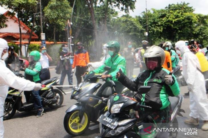 Pengojek daring mengikuti penyemprotan disinfektan untuk mencegah penularan COVID-19 di depan Gedung Negara Grahadi Surabaya, Minggu (22/03/2020). (ANTARA Jatim/ Hanif Nashrullah)