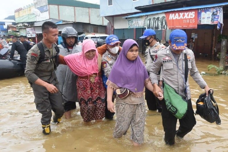 Anggota Polda Papua membantu warga terdampak banjir di kawasan Pasar Youtefa, Jumat (7/1/2022). (ANTARA/HO-Humas Polda Papua)