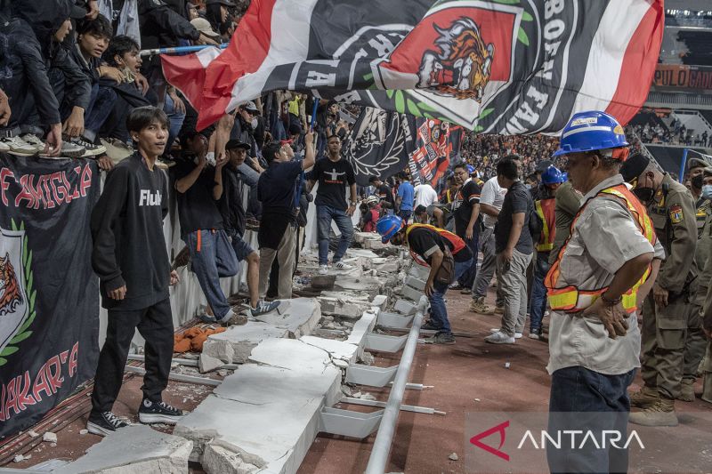Sejumlah penonton berdiri di atas puing pagar pembatas yang roboh saat peresmian Stadion Jakarta International Stadium (JIS) di Jakarta, Minggu (24/7). ANTARA FOTO/Muhammad Adimaja/pras.