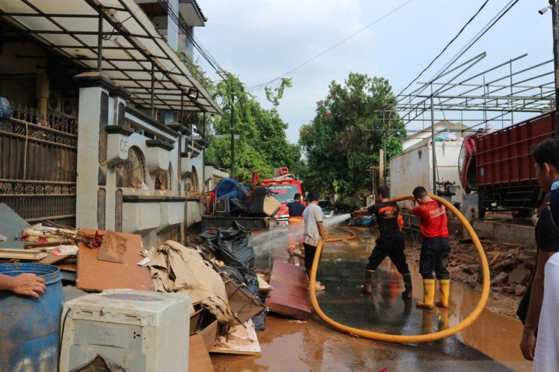 Petugar Damkar sektor Pesanggrahan, Jakarta Selatan membersihkan jalanan rumah warga yang tertimbun lumpur usai banjir di IKPN Bintaro, Sabtu (4/1/2020) (ANTARA/Laily Rahmawaty)