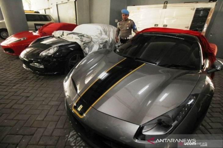 Polisi menjaga sejumlah mobil mewah yang diamankan di Polda Jawa Timur, di Surabaya,, Senin (16/12/2019). (ANTARA FOTO/Didik Suhartono)