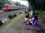 Libur Akhir Pekan, Warga Piknik Sambil Menikmati Lalu Lalang KRL di Taman Tanah Kusir