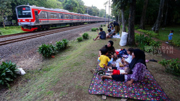 Libur Akhir Pekan, Warga Piknik Sambil Menikmati Lalu Lalang KRL di Taman Tanah Kusir