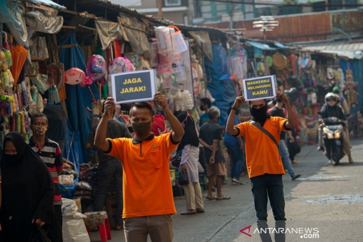 Petugas pengelola pasar berkampanye pencegahan COVID-19 dengan membawa poster berisi pesan di Pasar Jatinegara, Jakarta, Kamis (11/6/2020). (ANTARA FOTO/Aditya Pradana Putra/nz)