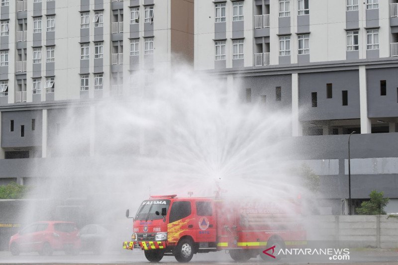 Relawan Badan Nasional Penanggulangan Bencana (BNPB) mengoperasikan mobil pemadam kebakaran untuk menyemprotkan disinfektan di kompleks Wisma Atlet, Kemayoran, Jakarta, Sabtu (21/3/2020). ANTARA FOTO/M Risyal Hidayat/aww. (ANTARA FOTO/M RISYAL HIDAYAT)