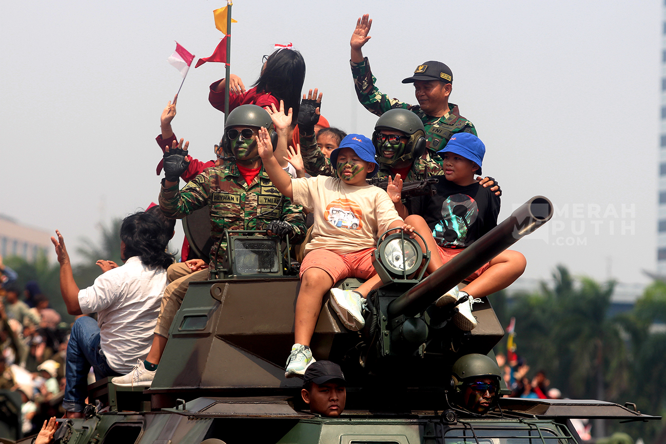 Wajah bahagia warga naik Tank Lapis Baja dalam parade defile alat utama sistem senjata (alutsista) milik TNI dalam peringatan Hari Ulang Tahun (HUT) ke-79 TNI di Lapangan Silang Monas, Jakarta Pusat, Sabtu (5/10/2024).