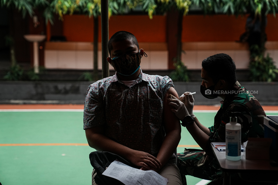 Vaksinator menyuntikan vaksin Covid-19 Sinovac kepada pelajar saat Vaksinasi Massal Pelajar Serentak di 14 Provinsi di SMAN 1 Kota Tangerang, Banten, Rabu, (14/7/2021). Badan Intelejen Negara (BIN) Provinsi Banten bersama Pemeritah Kota Tangerang dan TNI-POLRI menyelenggarakan vaksinasi massal pelajar guna mendukung program percepatan program vaksinasi nasional. Vaksinasi tersebut dilakukan serentak di 14 Provinsi yang tersebar di Indonesia. Merahputih.com / Rizki Fitrianto