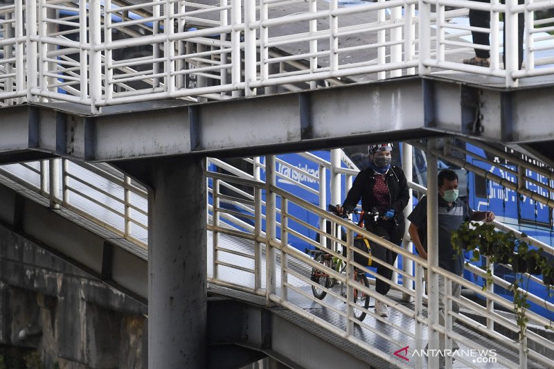 Seorang calon penumpang membawa sepeda menuju Halte Transjakarta Harmoni, Jakarta, Kamis (4/6/2020). Pemprov DKI Jakarta memperpanjang Pembatasan Sosial Berskala Panjang (PSBB) sekaligus sebagai masa transisi menuju tatanan normal baru, dengan salah satu kebijakannya tetap mempertahankan kuota 50 persen untuk kapasitas kendaraan pribadi dan transportasi massal. ANTARA FOTO/Wahyu Putro A/aww. (ANTARA FOTO/WAHYU PUTRO A)