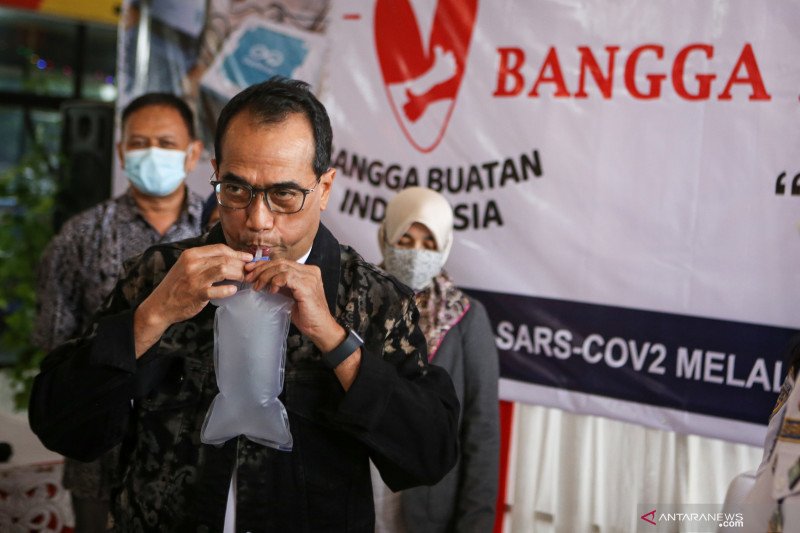 Menteri Perhubungan Budi Karya Sumadi menghembuskan nafasnya pada kantong nafas untuk dites dengan GeNose C19 di Terminal Kampung Rambutan, Jakarta, Minggu (24/1/2021). (Foto: Antara)