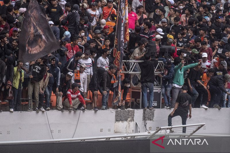 Sejumlah penonton berdiri di pagar pembatas yang roboh saat peresmian Stadion Jakarta International Stadium (JIS) di Jakarta, Minggu( 24/7/2022). Pagar pembatas penonton zona utara JIS roboh karena tidak dapat menahan beban orang yang duduk dan bersandar di pagar tersebut. ANTARA FOTO/Muhammad Adimaja/pras.