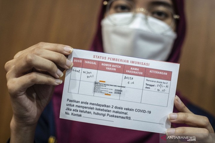 Tenaga kesehatasan menunjukkan kartu vaksinasi COVID-19 seusai disuntik vaksin CoronaVac di Puskesmas Cilincing, Jakarta, Kamis (14/1/2021). Tenaga kesehatan di wilayah Pemprov DKI Jakarta mulai disuntik vaksin COVID-19 buatan perusahaan farmasi Sinovac asal China. ANTARA FOTO/Aprillio Akbar