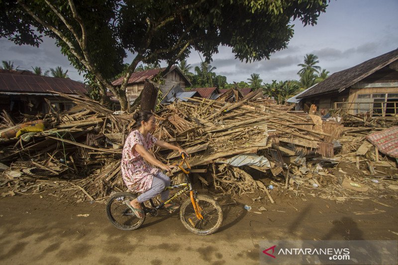 Warga menggunakan sepeda melintas di dekat puing-puing rumah akibat banjir bandang di Desa Waki, Kecamatan Batu Benawa,Kabupaten Hulu Sungai Tengah, Kalimantan Selatan, Rabu (20/1/2021). ANTARA FOTO/Bayu Pratama S/aww.