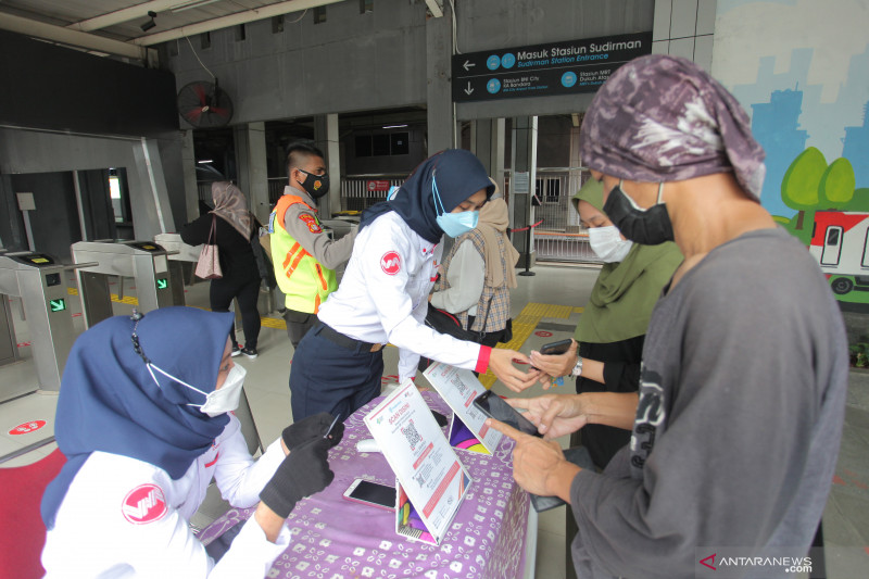 Petugas KAI Commuter membantu calon penumpang memindai kode batang (QR Code) melalui aplikasi PeduliLindungi sebelum menaiki KRL di Stasiun Sudirman,Jakarta, Sabtu (11/9/2021).