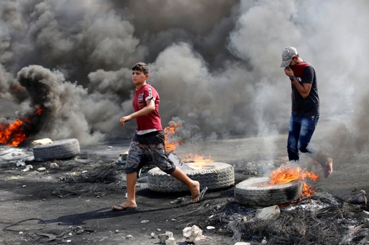 Pengunjuk rasa terlihat berjalan dekat ban terbakar saat jam malam, dua hari setelah protes anti-pemerintah nasional yang berubah menjadi kekerasan, di Baghdad, Irak, Kamis (3/10/2019). (Foto: Antara/REUTERS/WISSM AL-OKILI)