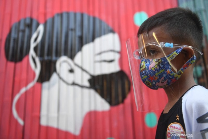 Seorang anak melintasi mural bertema COVID-19 di Jakarta, Senin (27/7/2020). Berdasarkan data dari Satgas Penanganan COVID-19 per 27 Juli 2020, kasus positif COVID-19 di Indonesia telah mencapai 100.303 kasus, dimana 58.173 orang dinyatakan sembuh dan 4.838 orang meninggal dunia. ANTARA FOTO/Akbar Nugroho Gumay/pras.