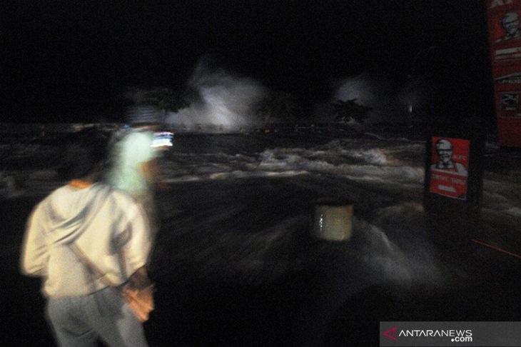 Sejumlah warga melihat ombak tinggi yang menerjang pesisir kawasan bisnis di Kota Manado, Sulawesi Utara, Minggu (17/1/2021). ANTARA FOTO/Adwit B Pramono/wsj. (ANTARA FOTO/ADWIT B PRAMONO)