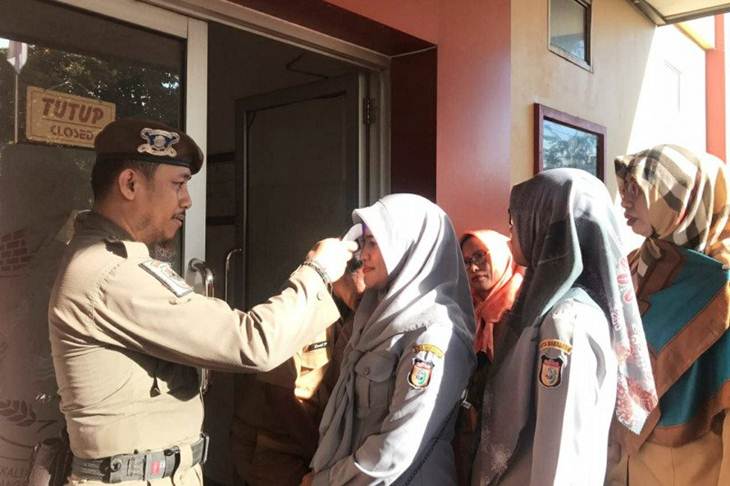 Sejumlah Aparatur Sipil Negara (ASN) Dinas Ketenagakerjaan Kota Makassar antre untuk diperiksa suhu tubuhnya menggunakan alat Infrared thermometer di Makassar, Sulawesi Selatan, Senin (16/3/2020).