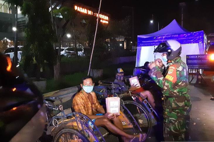 Petugas gabungan TNI dan Polri membagikan makanan untuk sahur kepada sejumlah warga di Kelurahan Kamal Muara, Penjaringan, Jakarta Utara, Minggu (26/4/2020) dini hari. ANTARA/Fauzi Lamboka