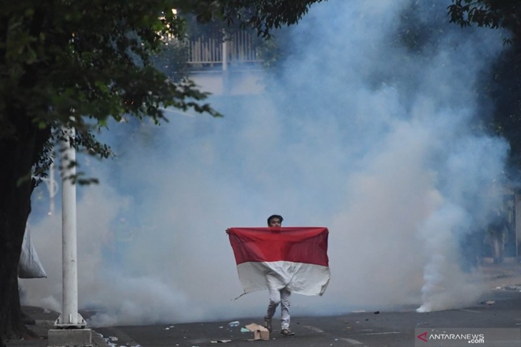 Seorang pengunjuk rasa yang menolak UU KPK hasil revisi dan RUU KUHP membawa bendera Merah Putih di kawasan dekat Kompleks Parlemen, Senayan, Jakarta, Senin (30/9/2019). ANTARA FOTO/Akbar Nugroho Gumay/wsj.