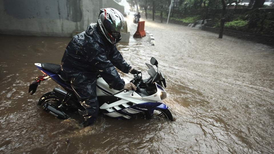 Pengendara sepeda motor melintasi banjir yang menggenangi kawasan Semanggi di Jakarta, Senin (11/12). Hujan deras disertai angin menyebabkan beberapa ruas jalan tergenang air dan pohon tumbang sehingga menyebabkan kemacetan lalulintas di beberapa kawasan. ANTARA FOTO/Muhammad Adimaja