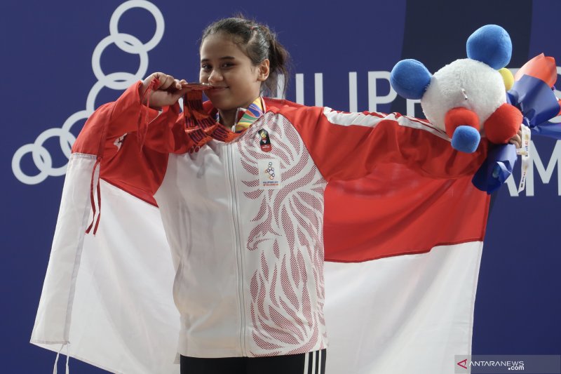 Lifter Indonesia Putri Aulia Andriani menunjukkan medali perunggu yang didapatkannya dari cabang olahraga angkat besi kelas 59 kilogram putri SEA Games 2019 di Kompleks Olahraga Rizal Memorial, Filipina, Selasa (3/12/2019). (Michael Siahaan)