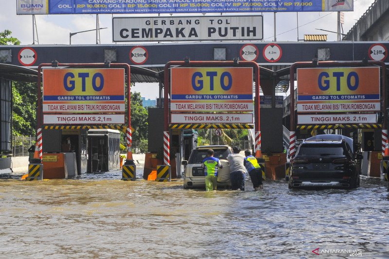 Sejumlah petugas membantu mendorong mobil yang mogok akibat banjir di Gerbang Tol Cempaka Putih, Jakarta Pusat, Minggu (23/2/2020). Menurut petugas banjir merendam pintu tol dari jam 03.00 WIB akibat luapan Waduk Ria Rio. ANTARA FOTO/ Fakhri Hermansyah/foc.