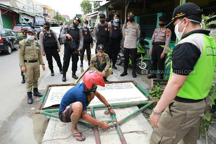 Petugas gabungan menurunkan papan nama penunjuk kantor FPI Surakarta, Jawa Tengah, Senin (4/1). (MP/Ismail)