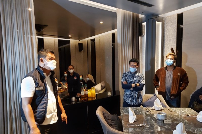 Direktur Reserse Narkoba Polda Metro Jaya Kombes Pol Mukti Juharsa (kanan) berbicara dengan pengunjung bar saat razia protokol kesehatan di D'Bunker Bar, Jumat dini hari (1/1/2021). ANTARA/Fianda Sjofjan Rassat